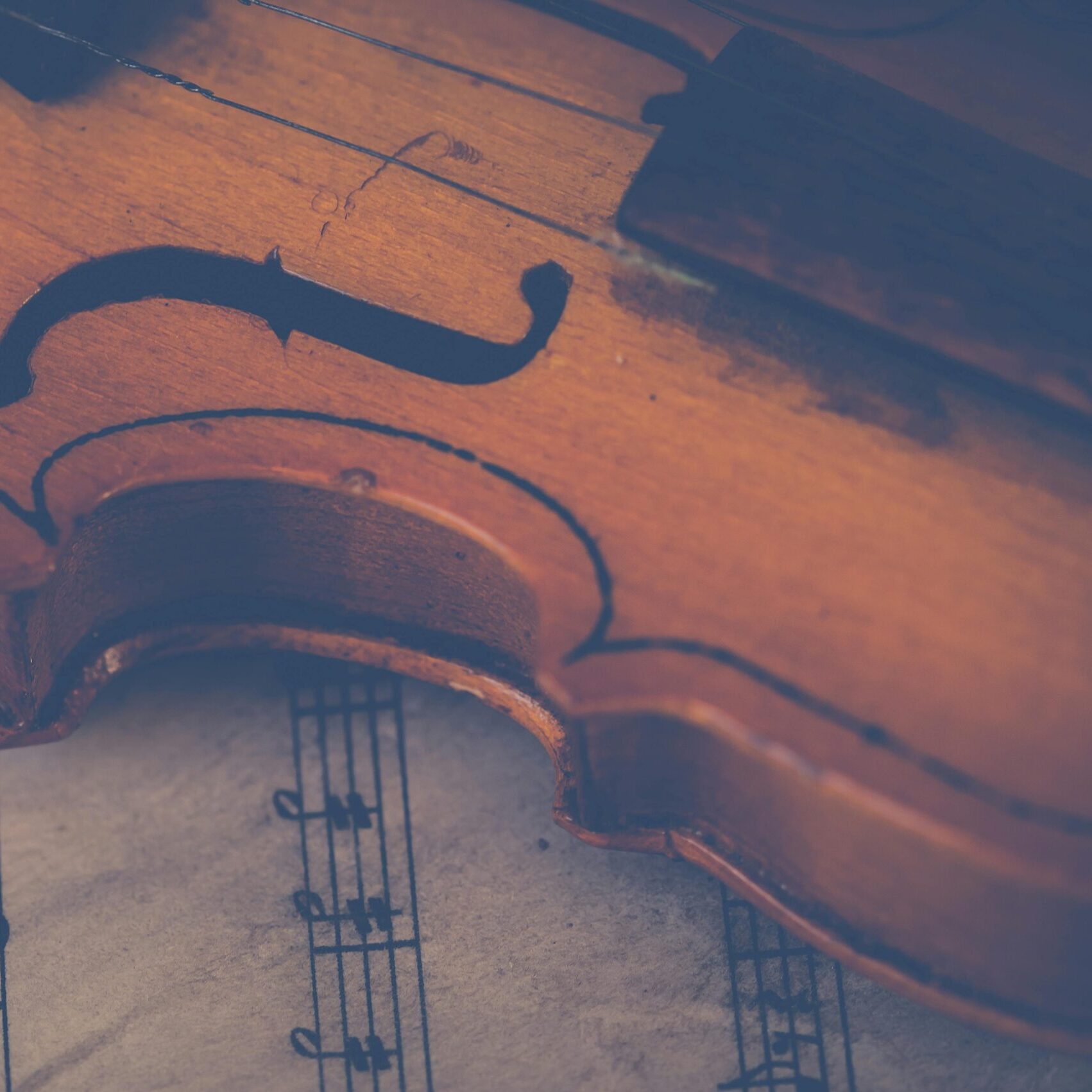 Artistic close-up of a violin on sheet music, highlighting musical elegance.